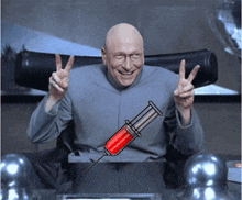 a man giving a peace sign next to a syringe with a red liquid on it