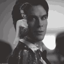a black and white photo of a man in a tuxedo and a woman in a dress with the caption devotion save me now
