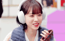a woman wearing headphones is smiling and holding a piece of chocolate