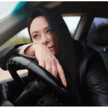 a woman sitting in a car with her head resting on the steering wheel