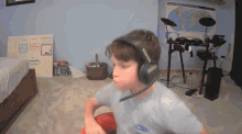 a young boy wearing headphones in front of a drum set in a room