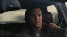 a man is driving a car and looking at the camera .