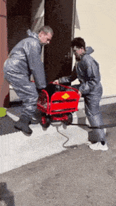 a man in a grey suit is pushing a red cart