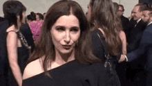 a woman in a black dress is making a funny face while standing in a crowd of people .