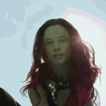 a woman with green hair and red highlights looks at the camera