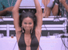 a woman in a black bikini is dancing with her arms in the air .