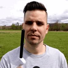 a man in a gray shirt holds a black object in his hand