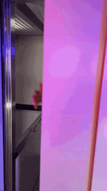 a person 's hand is visible behind a purple and blue wall