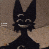 a black cat with three eyes and a smile on its face is sitting on a couch .