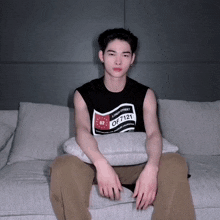 a man sits on a couch wearing a shirt that says loud street of 7121