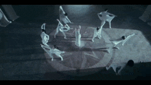 a group of dancers are dancing in a circle in a dark room .