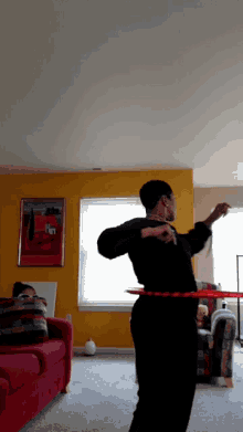 a woman is dancing with a red hula hoop in a living room