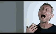 a man with a beard is crying with his mouth open and his hands outstretched .