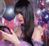 a woman in a purple dress is looking at her cell phone