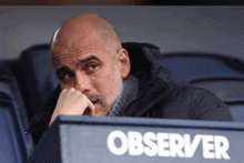 a bald man sits in a stadium with the word observer on the side