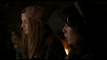 two girls are standing next to each other in the dark and one of them is wearing a varsity jacket .