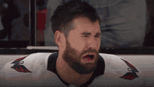a man with a beard wearing a white jersey with a red and black eagle on it