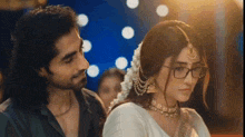 a man and a woman are looking at each other with the woman wearing glasses