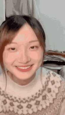 a woman wearing a sweater with a pattern on it is smiling