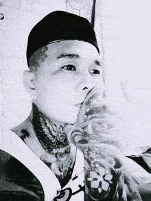 a black and white photo of a man with a tattoo on his arm and neck