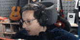 a man wearing headphones and glasses is talking into a microphone .