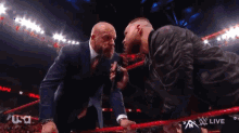 a man in a suit and tie is standing next to another man in a wrestling ring