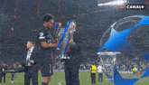 a soccer player holds a trophy in front of a sign that says canal +