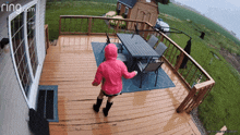 a woman in a pink jacket is dancing on a deck with a ring.com logo