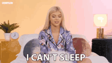 a woman in pajamas is sitting on a bed and says i can t sleep