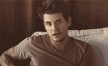 a young man is sitting on a couch with his arms crossed .