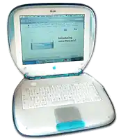 a blue and white ibook laptop is open to a page that says introducing more mac mini