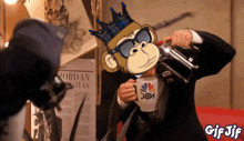 a man in a suit is pouring a cup of coffee from a nbc mug