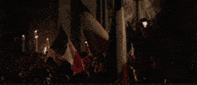 a crowd of people standing on a balcony with flags