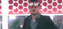a man wearing a santa hat and glasses is standing in front of a polka dot wall .