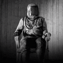 a black and white photo of a person in a gas mask sitting in a chair