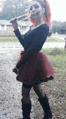 a woman in a black top and red skirt is holding a knife .