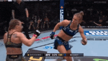 two women are fighting in a boxing ring with the ufc logo on the corner