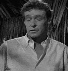 a black and white photo of a man with his eyes closed in a shirt .