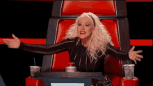 a woman with blonde hair is sitting in a chair with her arms outstretched .