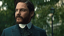 a man with a beard is wearing a blue suit and white collar