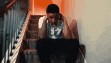 a man is sitting on a set of stairs holding his head .