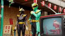 a man in a green and gold costume stands next to another man in a black costume