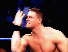 a man without a shirt is in a wrestling ring with his hand up