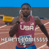 a man in a usa shirt is running on a track and says here it comes $ .