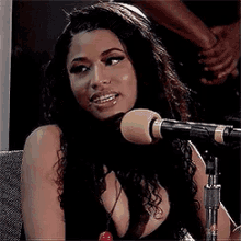 a woman is singing into a microphone while holding a lollipop .