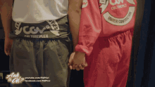 a couple holding hands in front of a sign that says " anh ta ai "