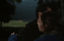 a man and a woman are hugging in the dark .