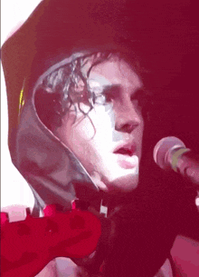 a man singing into a microphone wearing a hooded jacket
