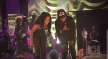 a man wearing a hoodie that says i 'm the greatest stands next to a woman on a stage