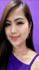 the woman is wearing a purple top and a necklace .
